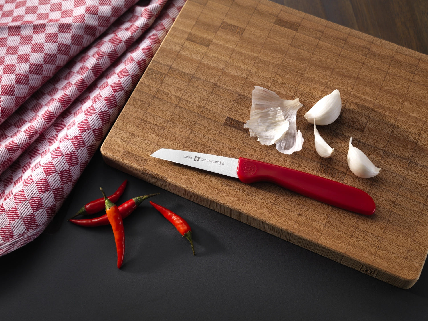 Das Zwilling Kitchen Twin Grip Gemüsemesser in Rot mit 70 mm Klinge vereint Funktionalität und Komfort für müheloses Schneiden von Gemüse.