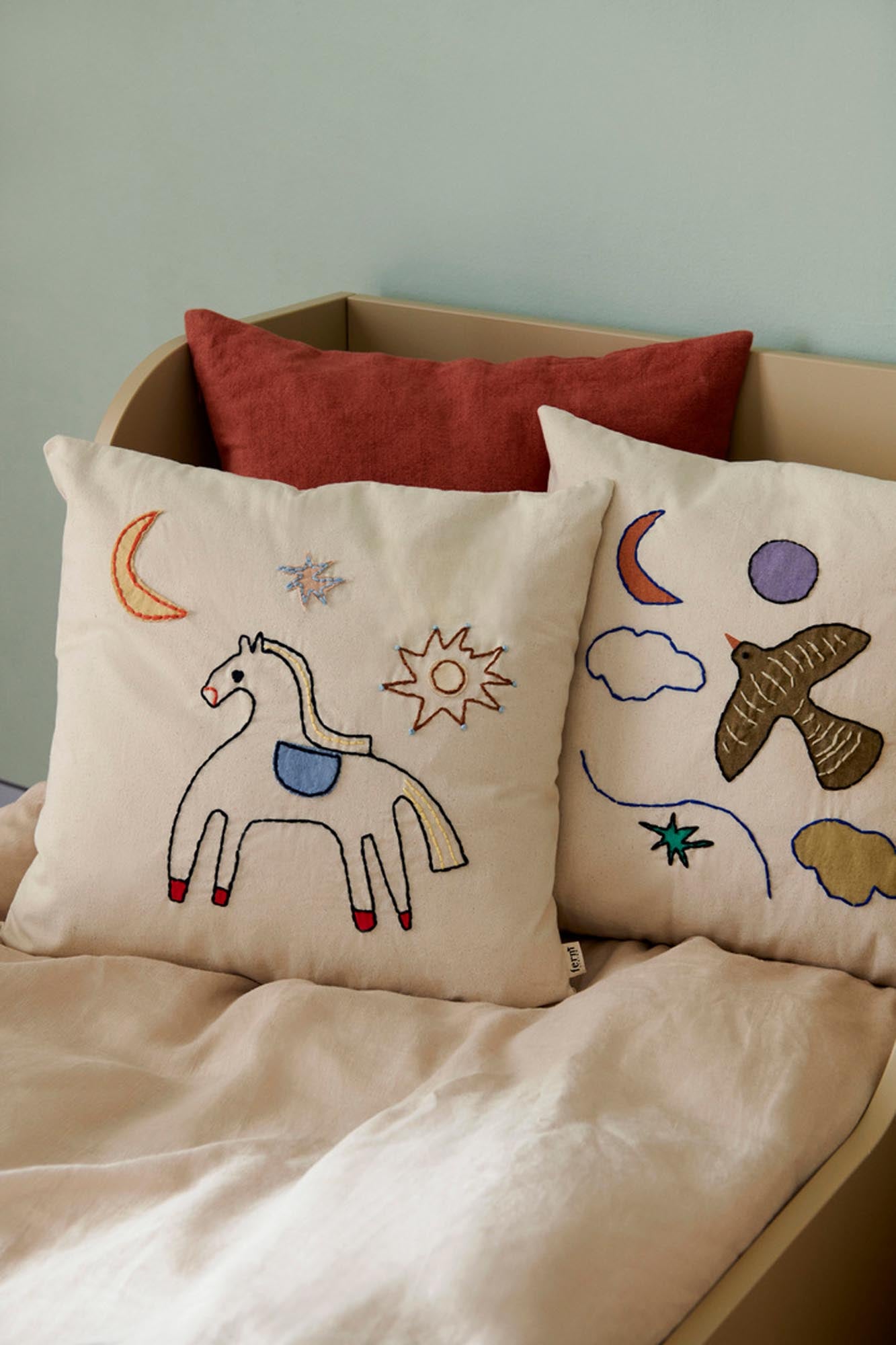 Die Naïve-Kissen von Ferm Living vereinen Nachhaltigkeit und Komfort, ideal für kreative Kinderzimmer mit handgestickten Motiven.