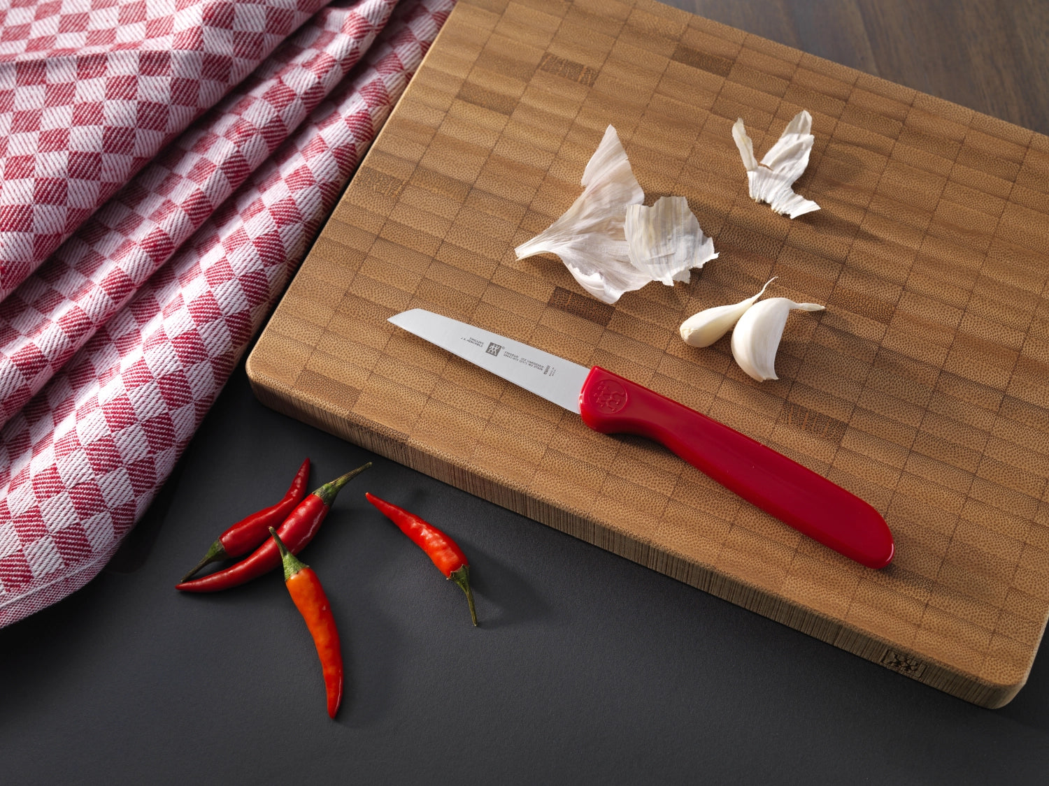 Das rote Twin Grip Gemüsemesser von Zwilling Kitchen mit 70 mm Klinge bietet präzise Schnitte und liegt ergonomisch in der Hand, ideal für die Zubereitung von Gemüse.