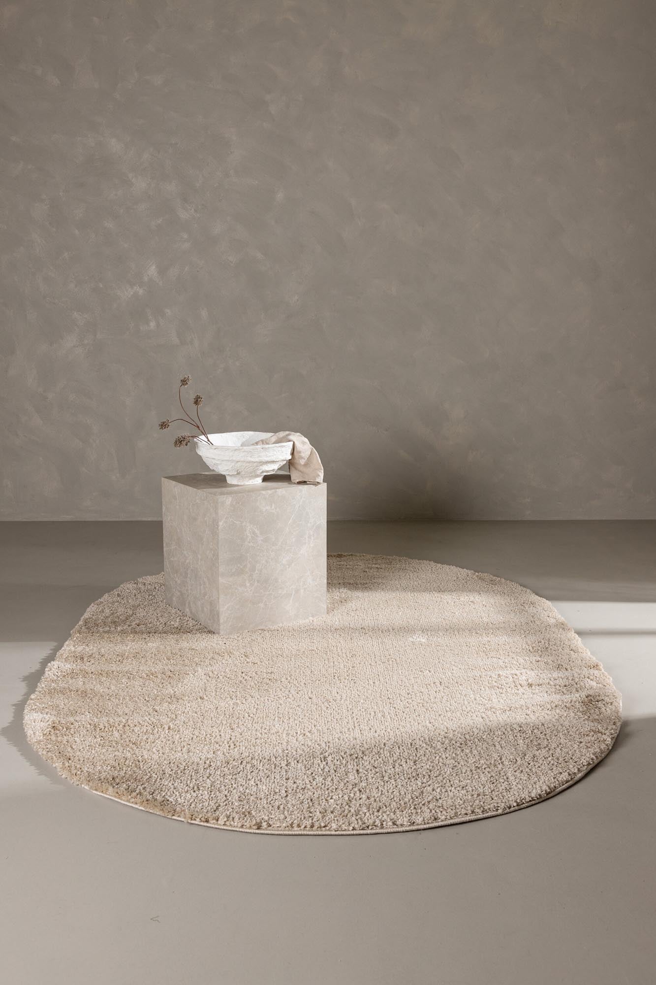 Eleganter ovaler Walter Pluto Teppich in sanften Beigetönen, ideal für stilvolle Wohnräume, erhältlich bei KAQTU Design AG.