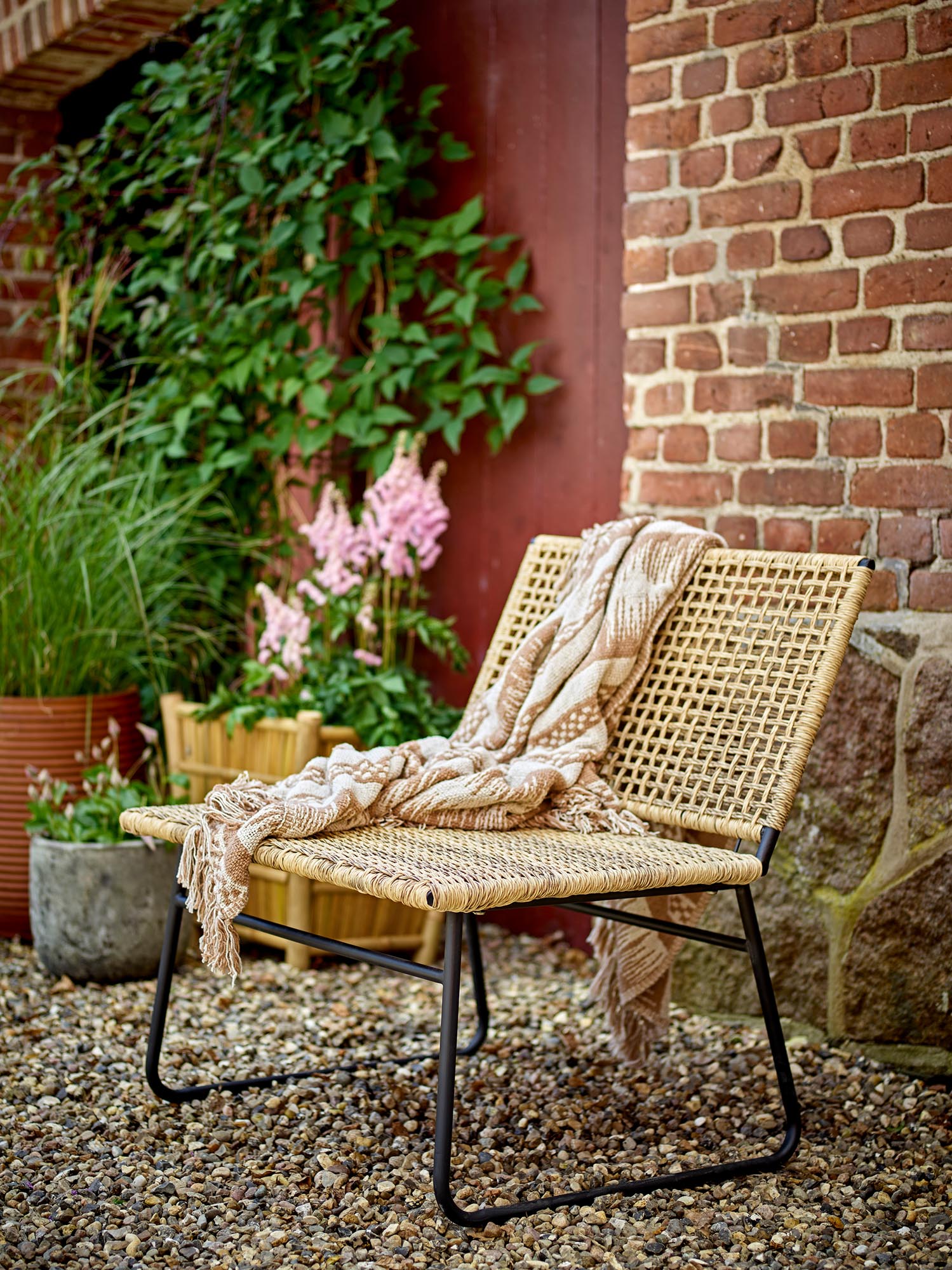 Eleganter Loungesessel aus Polyrattan, ideal für drinnen und draussen, bietet Komfort und skandinavisches Design.