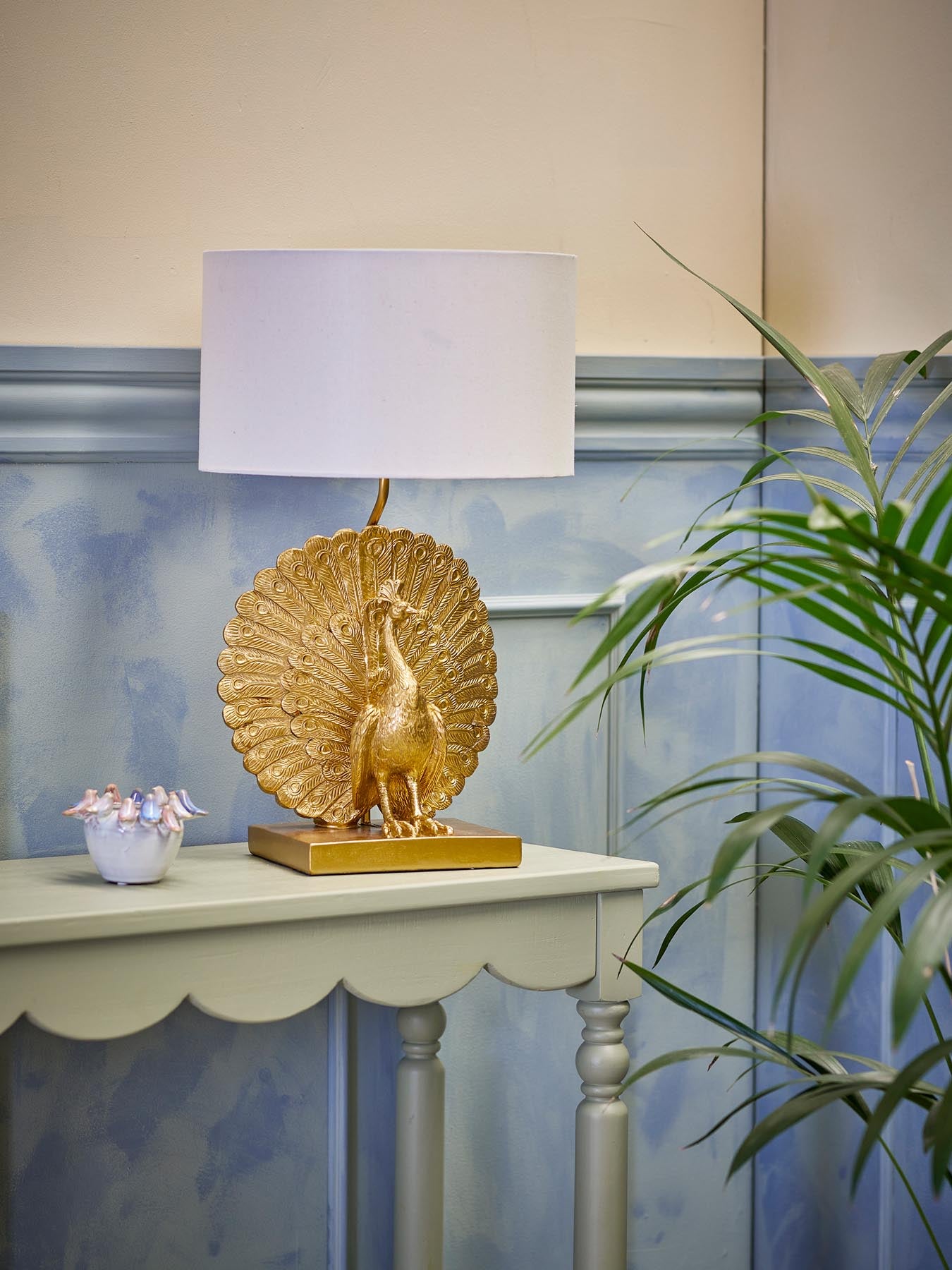 Entdecken Sie die elegante Peacock Tischlampe in Gold von Creative Collection. Ein stilvolles Highlight für jedes Zuhause, das Licht und Kunst vereint.