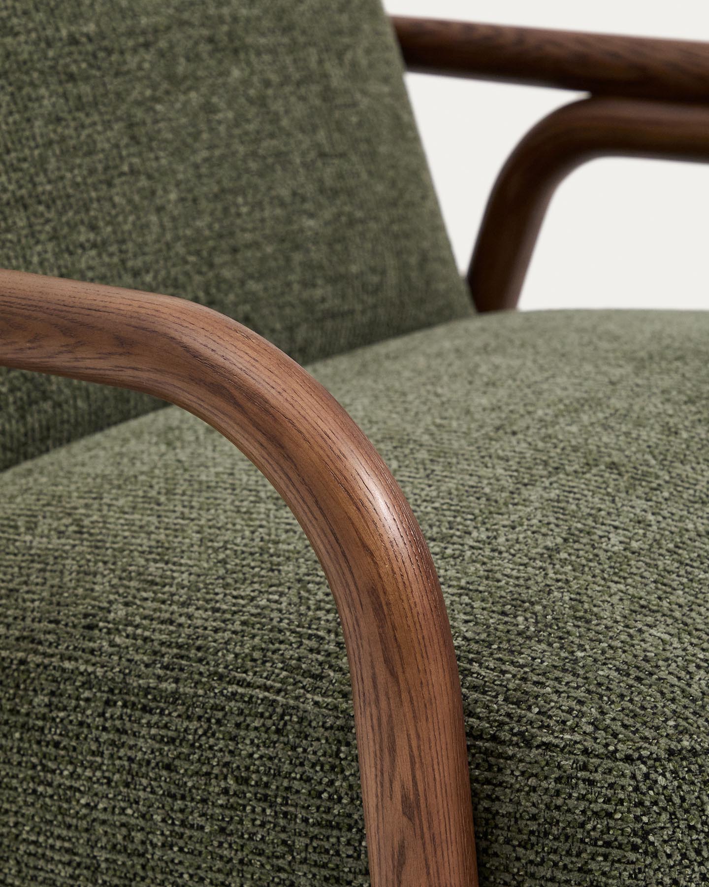 Eleganter Sessel Sylo in dunklem Grün aus Chenille, kombiniert mit robustem Eschenholz und einem warmen Nussbaum-Finish, ideal für jedes Wohnambiente.