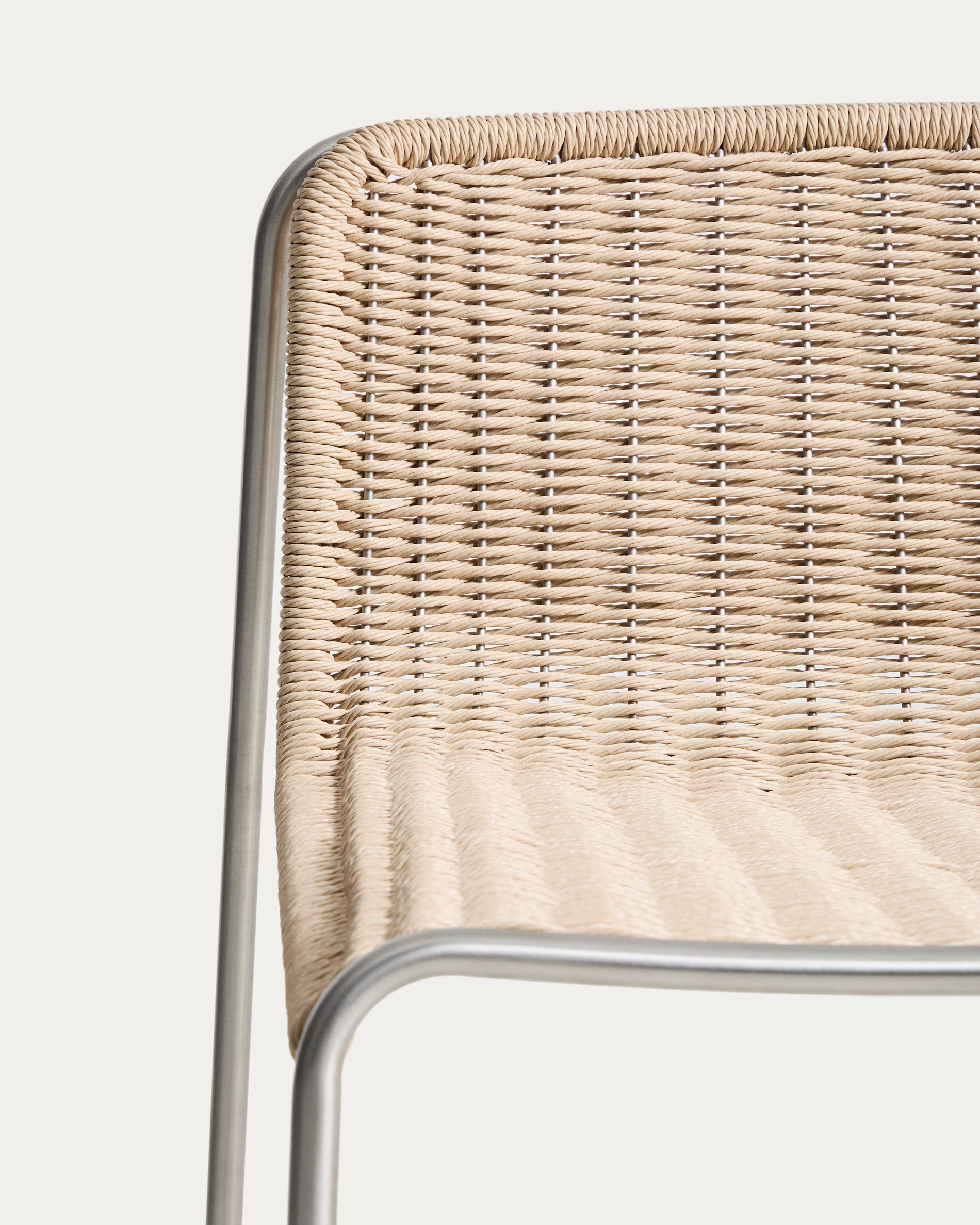 Moderner Stapelhocker Tavari in sanftem Beige, aus robustem Synthetikseil und gebürstetem Edelstahl, ideal für stilvolle Outdoor-Bereiche.