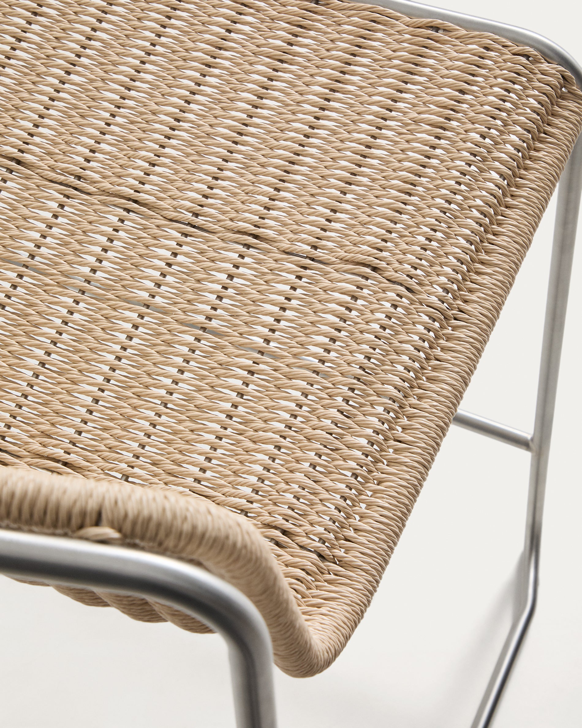 Eleganter Stapelhocker Tavari in hellem Beige, gefertigt aus strapazierfähigem Synthetikseil und gebürstetem Edelstahl, perfekt für den Außenbereich.
