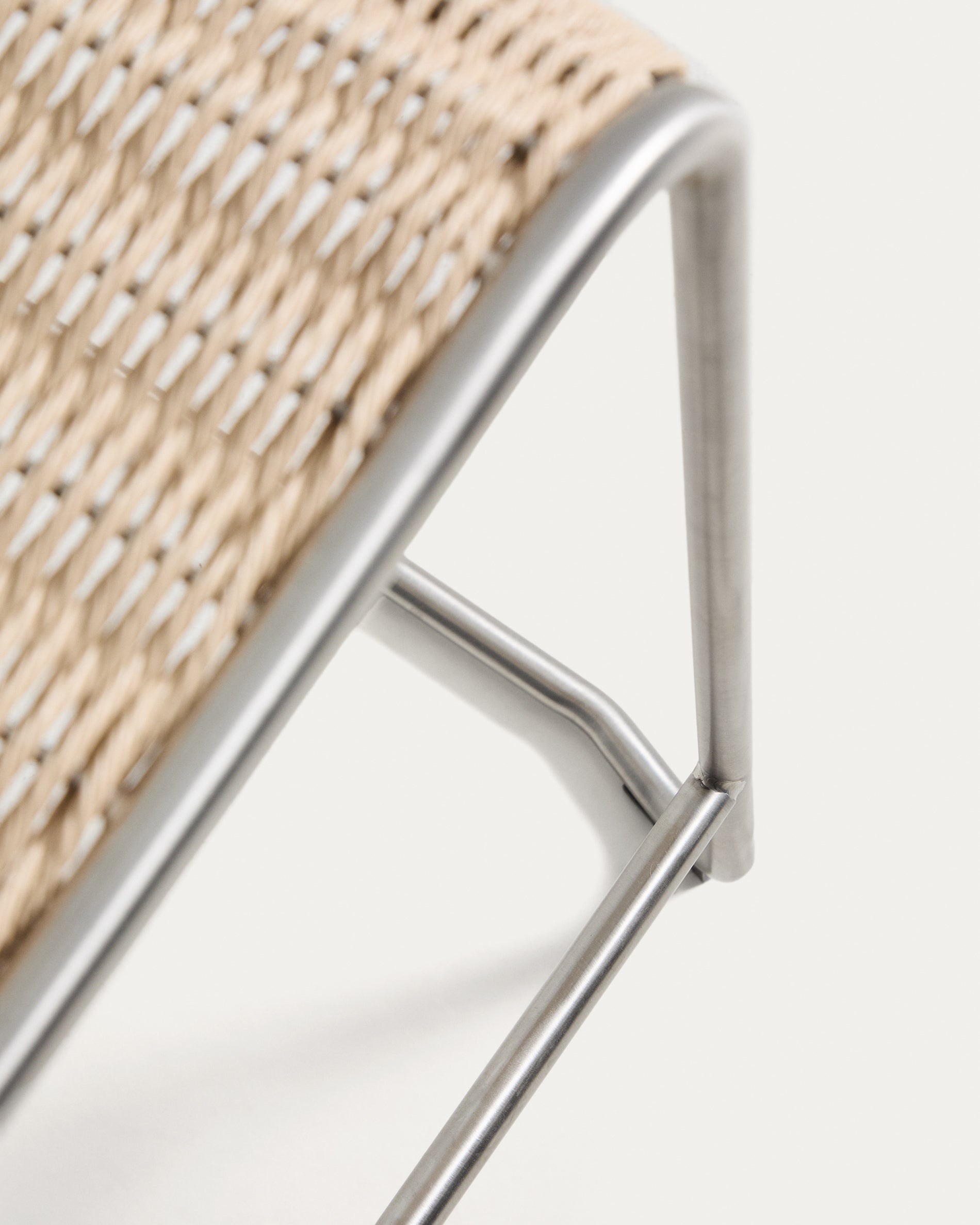 Eleganter Stapelhocker Tavari in hellem Beige, gefertigt aus strapazierfähigem Synthetikseil und gebürstetem Edelstahl, perfekt für den Außenbereich.