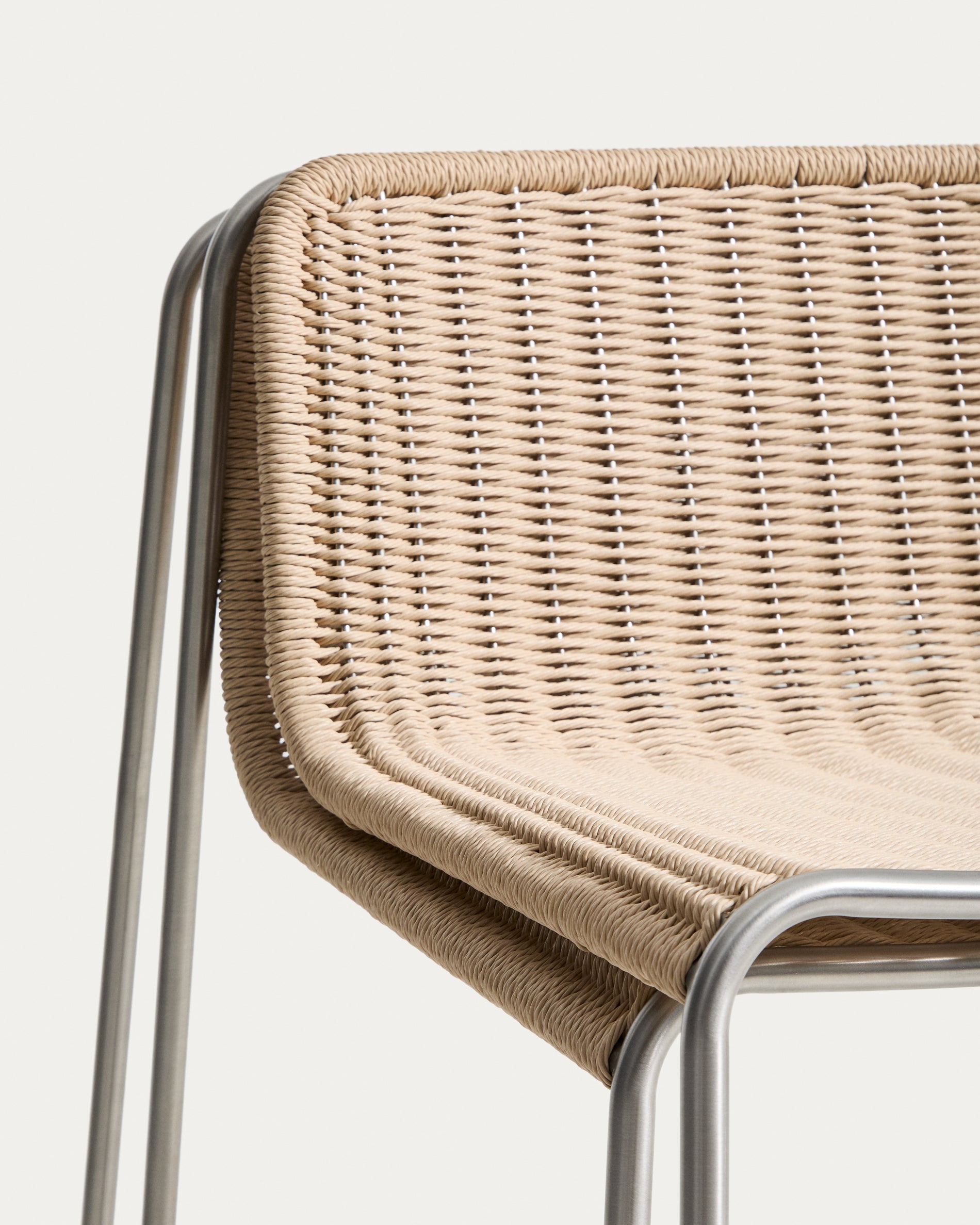 Moderner Stapelhocker Tavari in sanftem Beige, aus robustem Synthetikseil und gebürstetem Edelstahl, ideal für stilvolle Outdoor-Bereiche.