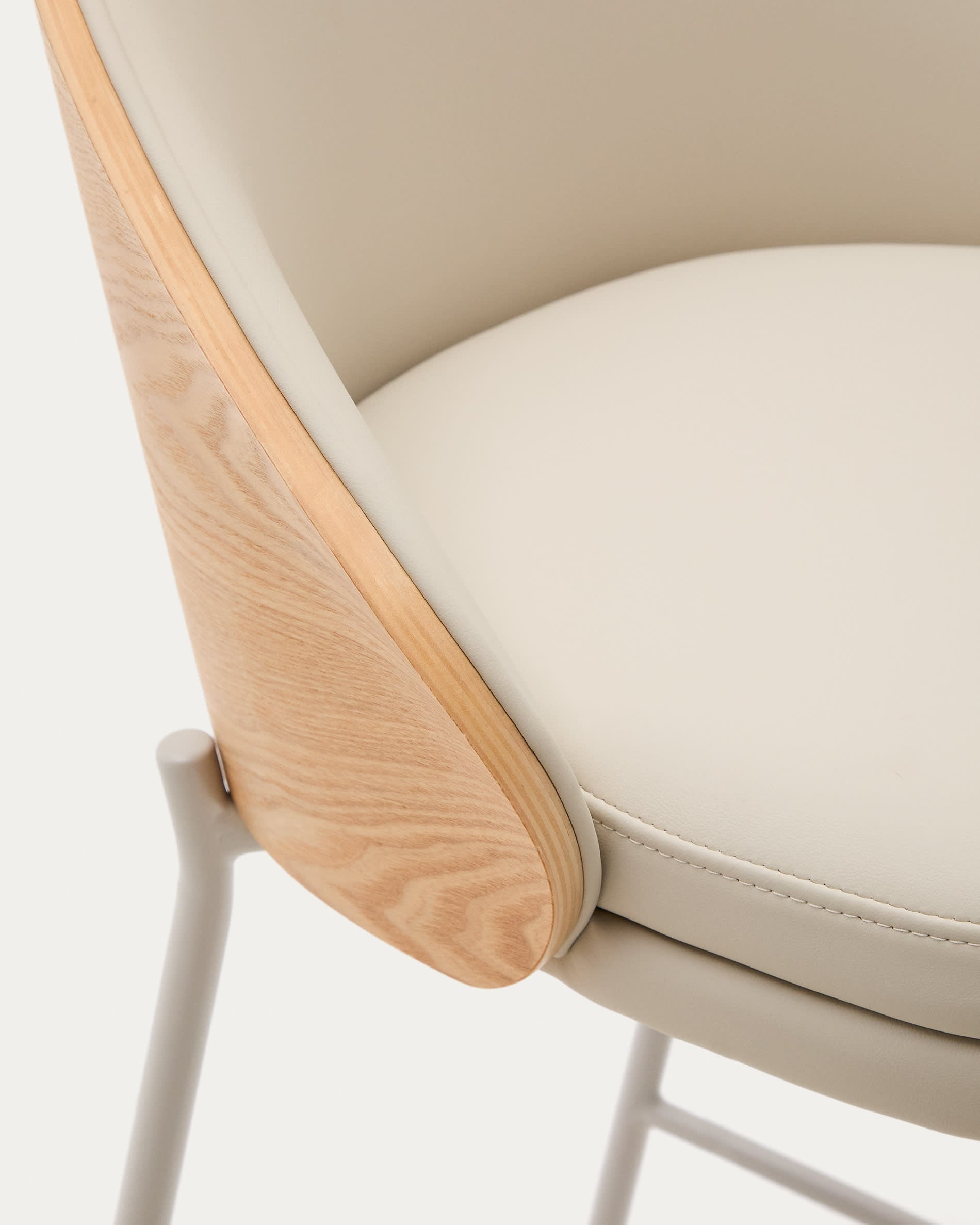 Der Eamy Hocker vereint stilvolles Kunstleder in Beige, langlebiges Eschenfurnier und schicke Metallakzente für ein modernes Wohnambiente.