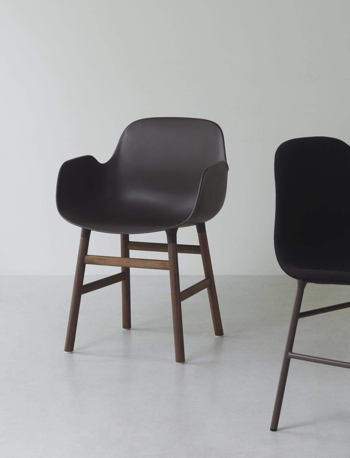 Eleganter Form Lehnstuhl in Hellgrau mit Walnuss-Akzenten, ideal für stilvolle Wohnräume und gemütliche Leseecken.