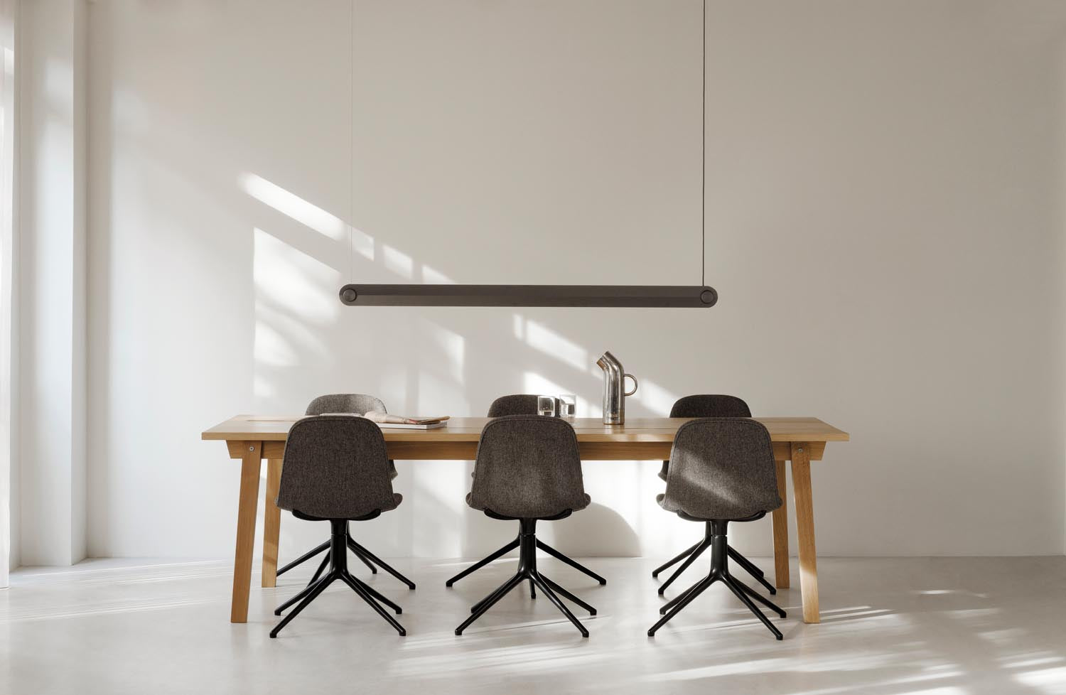 Eleganter hellgrauer Drehstuhl aus Aluminium von Normann Copenhagen, ideal für stilvolle Büros und gemütliche Wohnräume.
