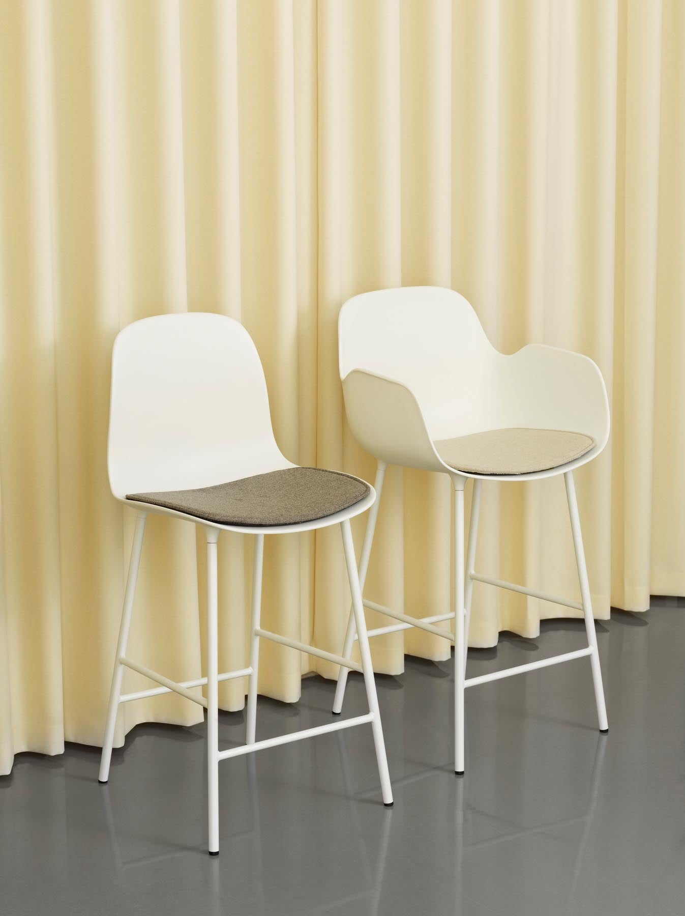 Erleben Sie den Form Barstuhl mit Armlehne 65 cm von Normann Copenhagen – ein elegantes Design aus langlebigem Stahl und warmem Grau, perfekt für stilvolle Küchen.