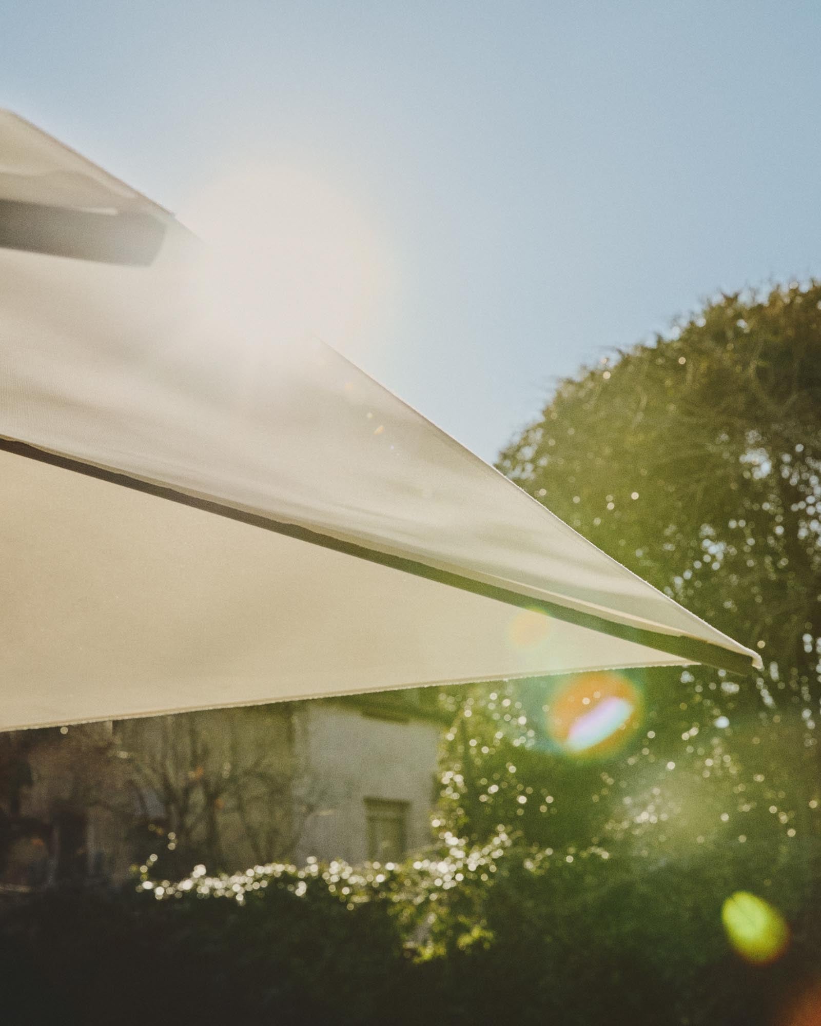Exzentrischer Sonnenschirm Noli in elegantem Beige, kombiniert mit einem modernen grünen Aluminiumgestell, perfekt für entspannte Stunden im Freien.
