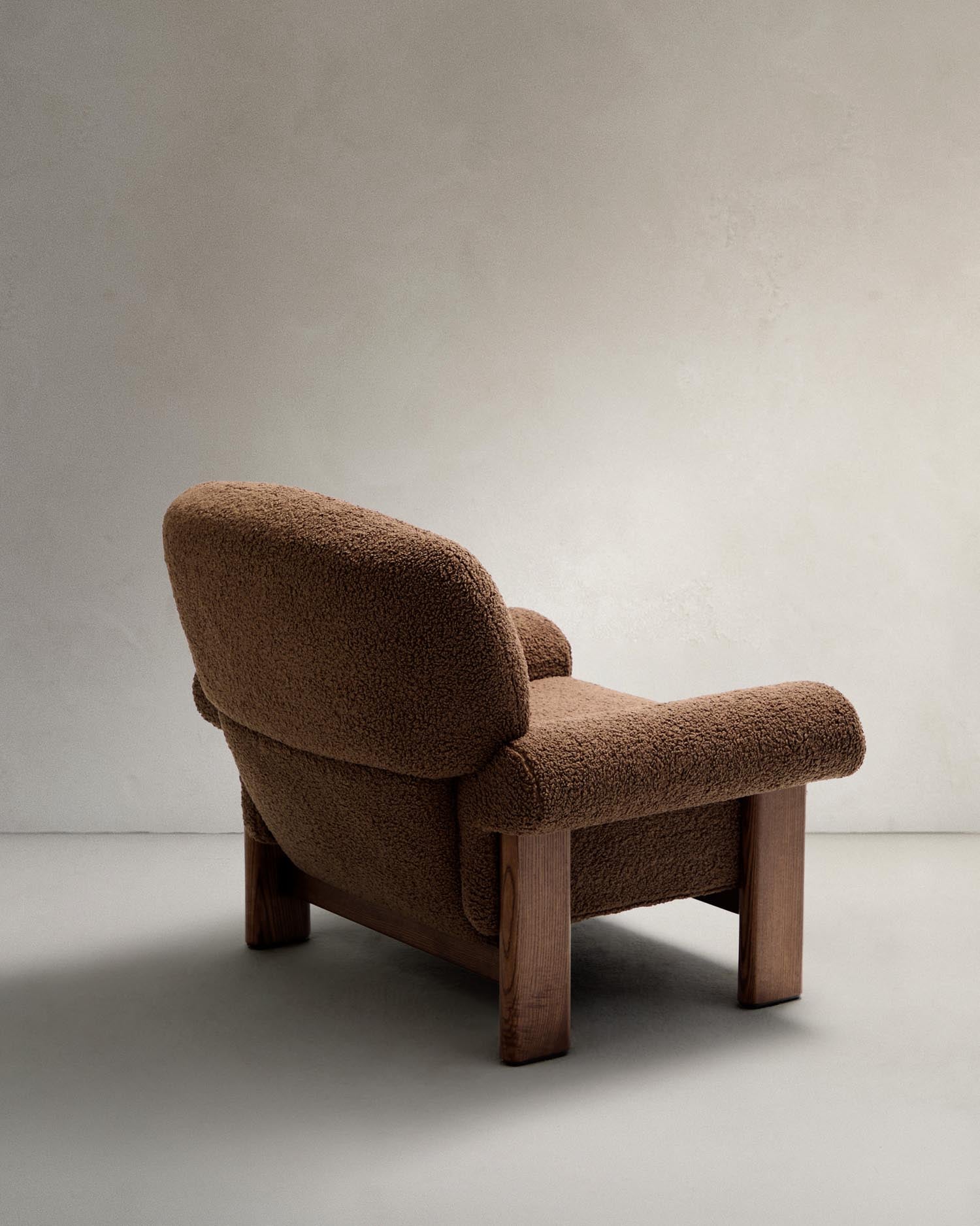 Eleganter Sessel Nema in taupefarbenem Bouclé, kombiniert mit robustem Eschenholz. Perfekt für ein modernes und nachhaltiges Zuhause.